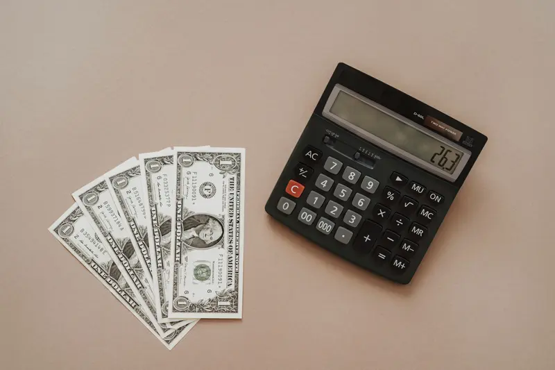 Five one-dollar bills fanned out next to a desk calculator